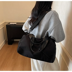 Détail d'un grand sac fourre-tout noir en nylon montrant la texture et la poche zippée latérale
