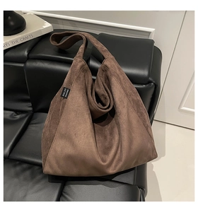 Detail of a brown suede hobo tote bag on a bench showing texture and leather label