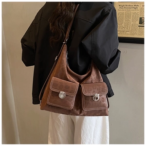 Close-up of brown vintage hobo bag with front pockets and white contrast stitching