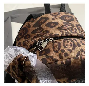 Detail of silver dual zippers on leopard print backpack with white lace bow decoration