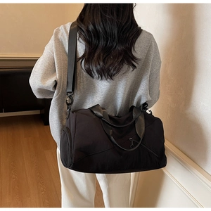 Détail d'un grand sac fourre-tout noir en nylon avec large bandoulière sur le modèle