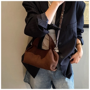 Detail of dark brown faux suede bucket bag showing soft texture and removable shoulder strap