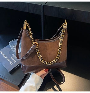 Detailed view of dark brown suede and leather splicing texture with gold chain strap