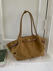 Brown suede tote bag with leather straps and drawstring detail in home setting
