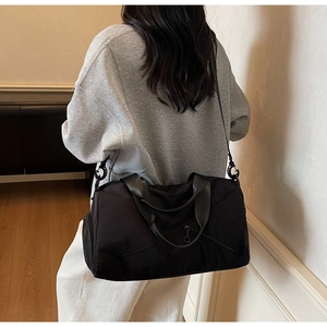 Détail du sac de voyage en nylon noir avec bandoulière ajustable porté par un modèle