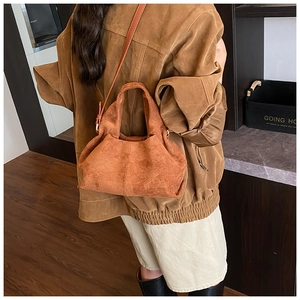 Brown faux suede bucket bag shown worn as a crossbody bag in a home setting
