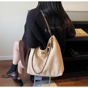 Detail of beige large tote bag with leather straps, chain shoulder and wooden bead decor