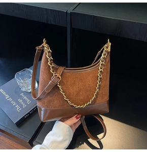 Detail of hobo bag featuring brown suede texture and decorative chunky gold chain strap