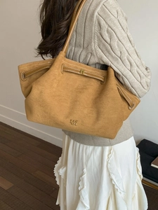 Large camel suede tote bag with pleated detail and gold logo shown on model shoulder
