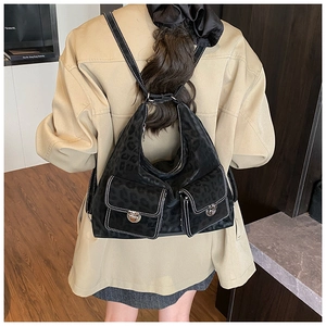 Detail of black leopard print backpack with multi-pocket design on female model