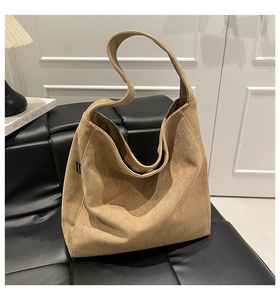 Detail of camel suede tote bag showing soft texture and wide shoulder strap on bench