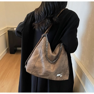Retro brown large tote bag with silver chain detail worn with a long black coat
