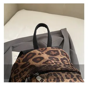 Detailed close-up of the leopard print backpack featuring black top handles and dual zippers
