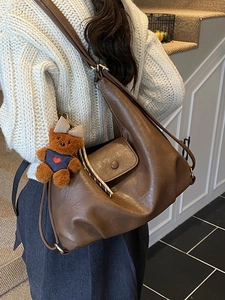 Brown soft PU leather tote bag with cute bear charm worn on a model in a stylish setting