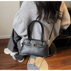 Chic black shoulder bag detail with retro gold buckle on model in an urban setting