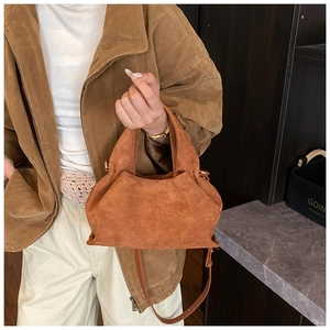 Detailed texture of brown suede dumpling bag with elegant pleats and cross-body strap