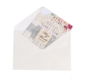 Detail of laser-cut wedding invitation with pink floral insert and silver glitter band