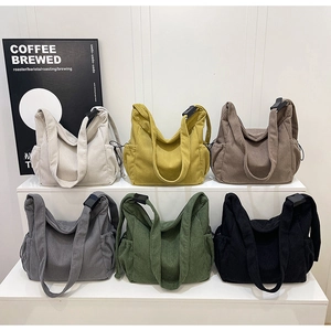 Macro detail of various corduroy tote bags with adjustable straps and side drawstrings