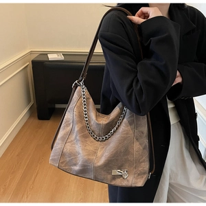 Detail of vintage brown tote bag featuring a chunky silver chain and heart lock charm