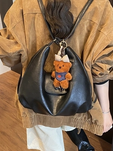 Chic black pleated faux leather crescent backpack for women with a cute teddy bear charm