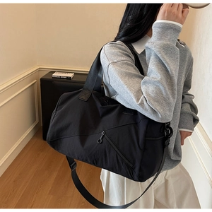 Détail du grand sac de voyage en nylon noir avec bandoulière large et fermeture éclair