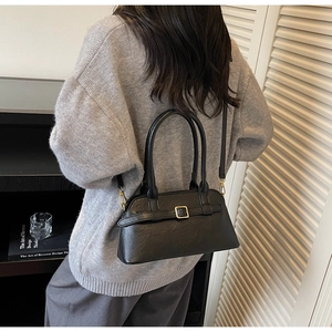Close-up of a black matte leather shoulder bag with decorative buckle and metal hardware