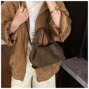 Gros plan sur un sac nuage en daim marron avec texture plissée et bandoulière réglable