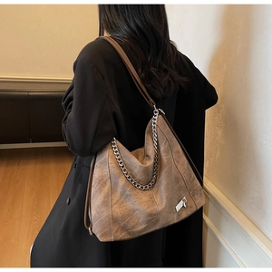 Close-up of vintage brown tote bag featuring metallic chain and leather shoulder strap