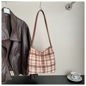 Classic plaid bucket bag featuring a gold bow detail and brown leather strap on a hanger