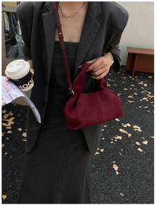 Detail of burgundy suede dumpling bag with soft pleats styled with a gray blazer