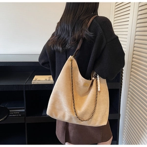 Detail of beige suede tote bag with woven chain strap and gold twist lock closure