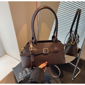 Detailed view of dark brown faux leather shoulder bag with gold buckle and smooth texture