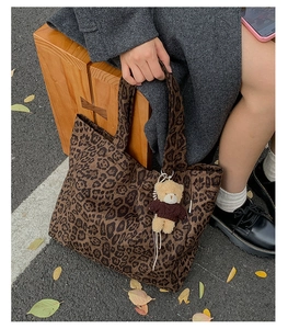 Detail view of large leopard print canvas tote bag with a cute teddy bear charm pendant