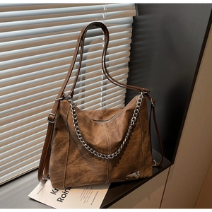 Detail view of brown vintage suede tote bag with silver chain and leather strap