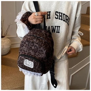 Close-up of leopard print backpack featuring white lace trim and textured fabric details