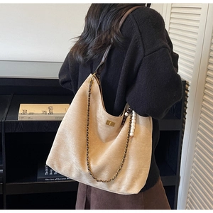 Detail of beige hobo bag in matte suede with chain strap and beaded charm decoration