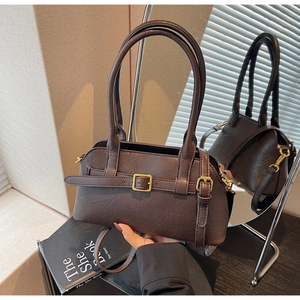 Detail of dark brown leather shoulder bag with buckle strap and mirror reflection view