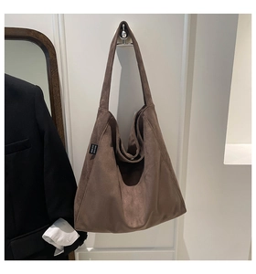 Brown suede tote bag with brand label displayed in a cozy home interior setting