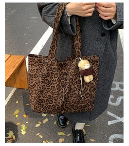 Detail of leopard print canvas tote bag featuring a cute teddy bear charm in autumn style