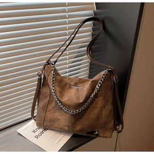 Detail of vintage brown frosted leather tote bag with silver chain and heart pendant