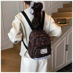 Detail view of mini leopard print backpack with white lace trim worn by a model