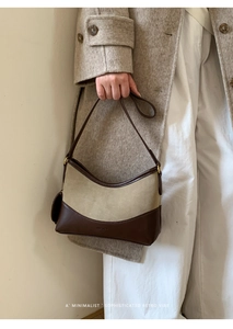 Detail of minimalist beige suede handbag with brown leather base and logo embossing