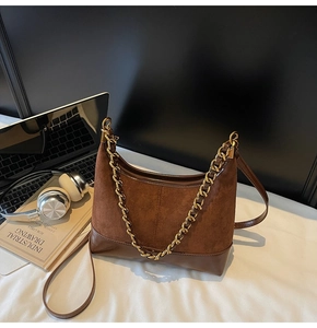 Detail of dark brown hobo bag with suede stitching and elegant gold chain strap