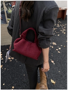 Detailed view of burgundy suede bucket bag with vintage gold metal hardware and strap