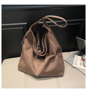 Detail of soft brown suede tote bag with side logo tag on a white leather seat