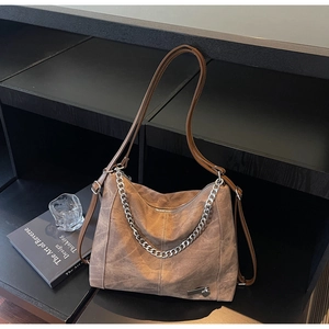 Macro detail of brown suede tote bag with metallic chain and heart charm detail