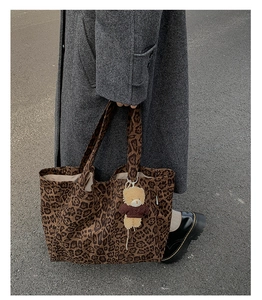 Close-up of leopard print canvas tote bag with a cute plush bear pendant on a street background