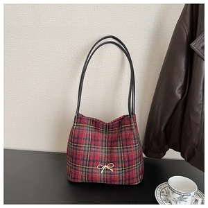 Detail of red and black plaid bucket bag with golden bow charm and retro British style