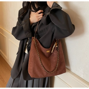 Macro view of dark brown suede hobo bag featuring vintage beads and golden clasp detail
