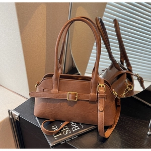 Detail view of brown faux leather handbag showing vintage buckle and natural grain texture
